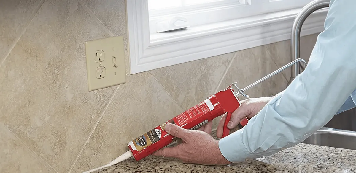 Handyman applying caulk along a kitchen backsplash and countertop seam in Evansville, IN